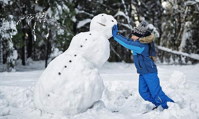 Una-nina-vestida-de-azul-con-un-muneco-de-nieve-iStock.jpg